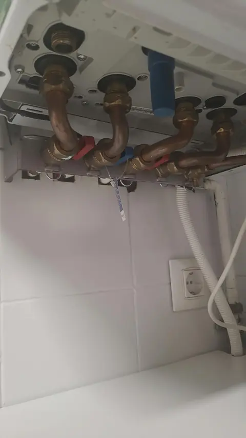 Conexiones hidráulicas de caldera de gas con llaves de corte de ida, retorno y agua sanitaria.