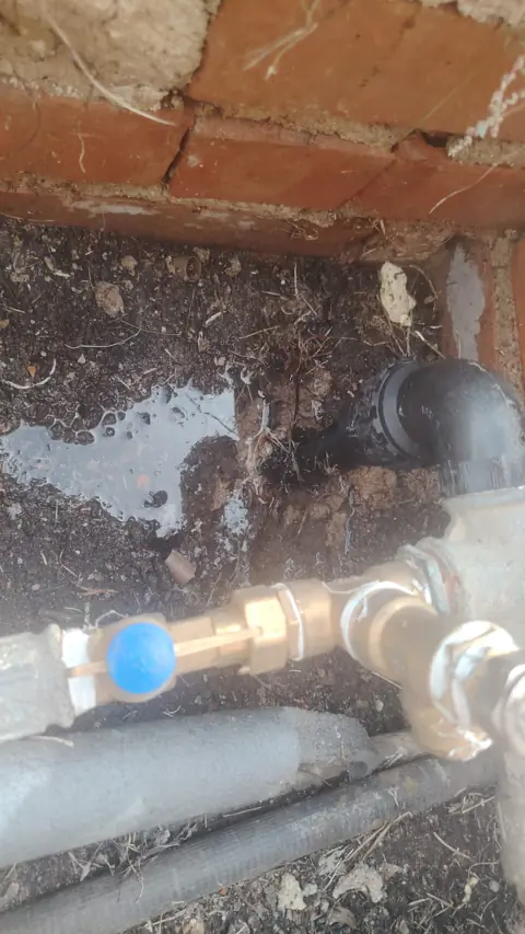 Localización y reparación de fuga de agua en arqueta de acometida exterior.