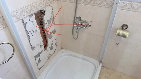 Apertura de pared en ducha para renovar el trazado de tuberías de agua fría y caliente.